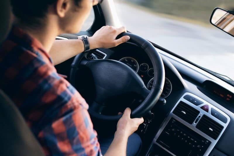 Person in a red plaid shirt driving a car