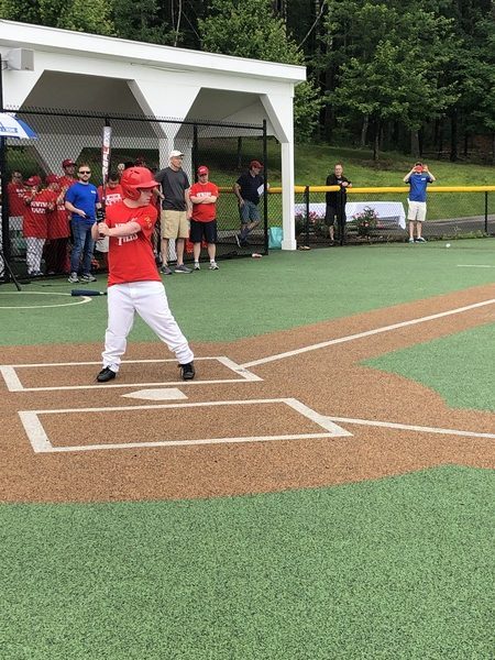 Child in a red t-shirt preparing to hit the ball in a baseball game