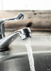 Close-up of a running water tap with a clear stream of water flowing into a stainless steel sink