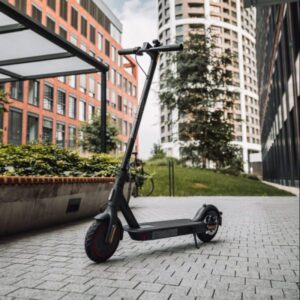 A modern electric scooter parked on a paved walkway between high-rise buildings